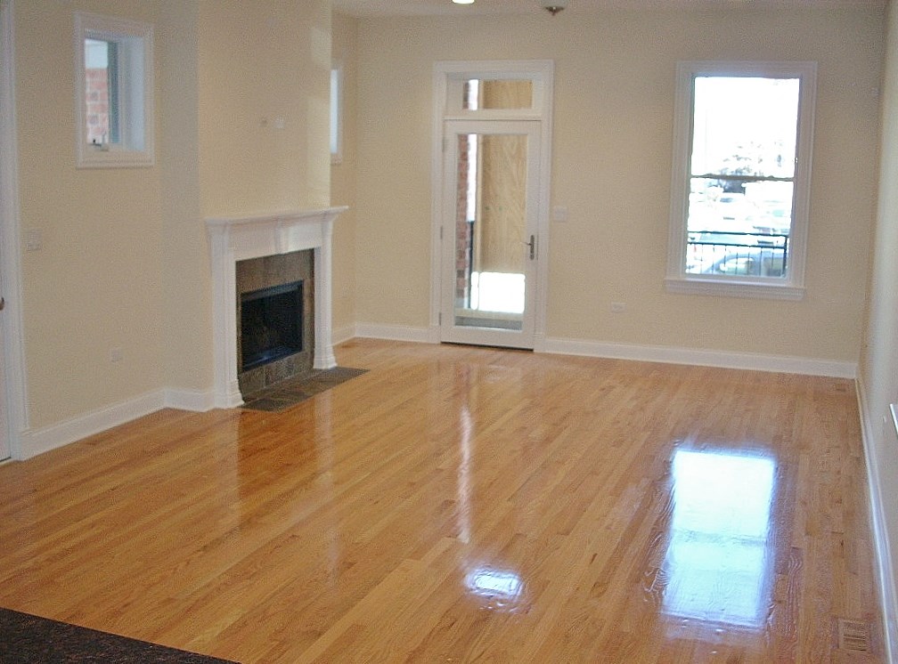 an empty living room with a fireplace and a wooden floor