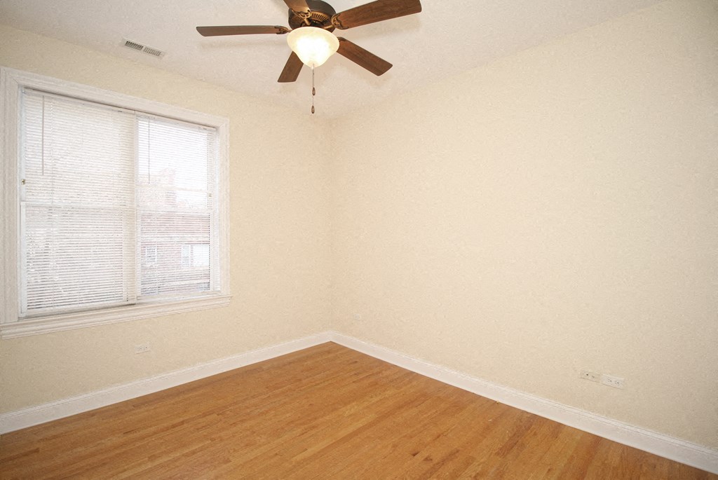 an empty room with a ceiling fan and a window