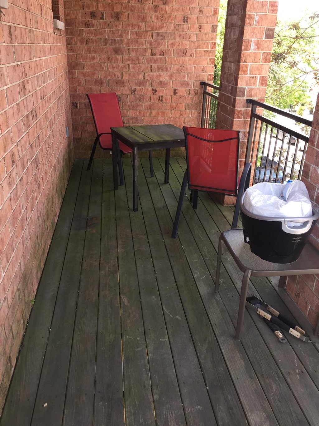 an empty porch with chairs and a table on a brick wall