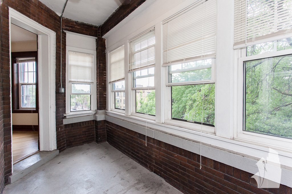 an empty room with large windows and a brick wall