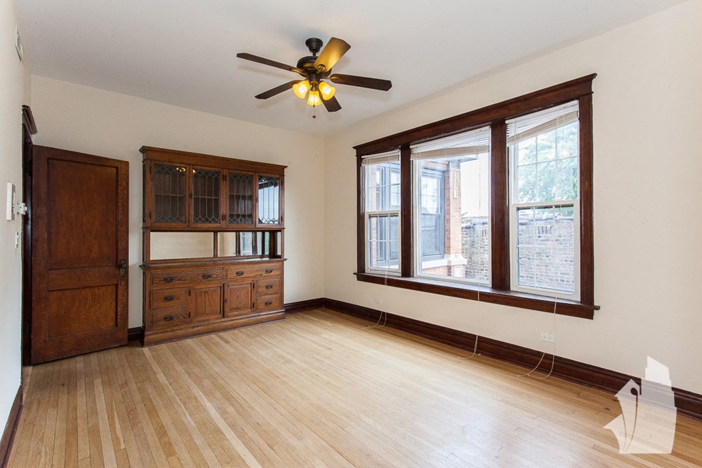 an empty living room with wood floors and a ceiling fan
