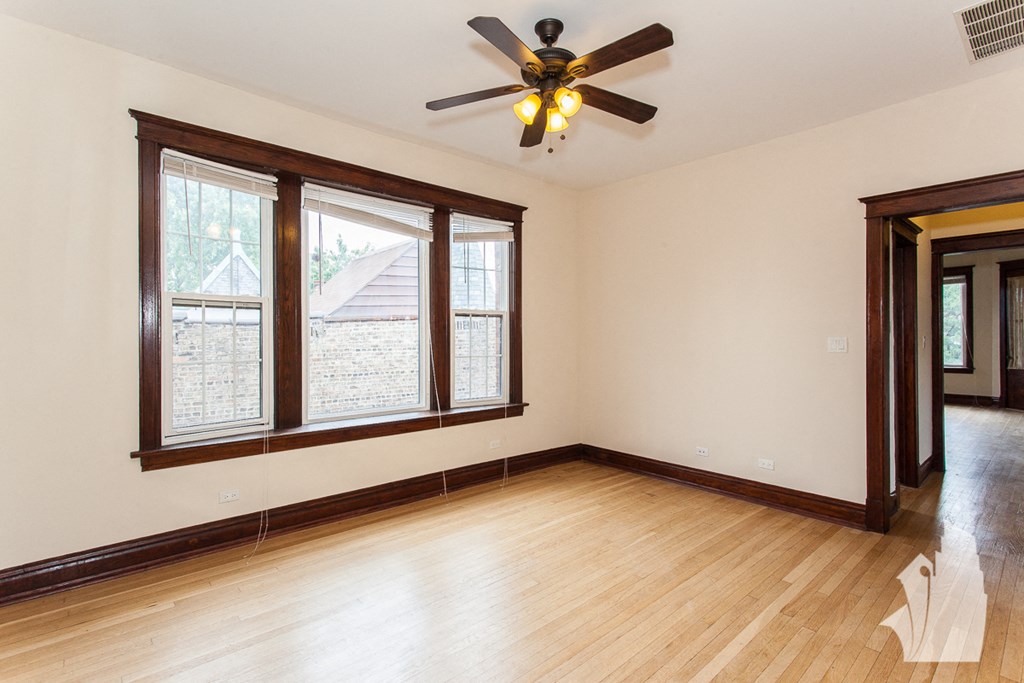 an empty living room with a ceiling fan and large windows
