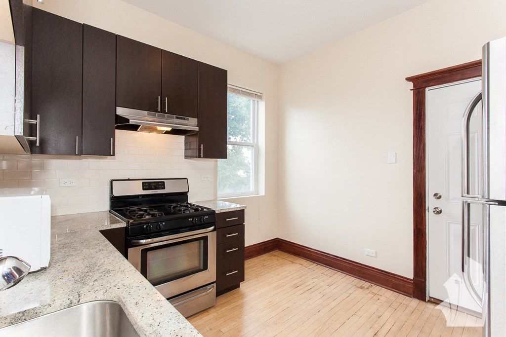 an empty kitchen with black cabinets and stainless steel appliances