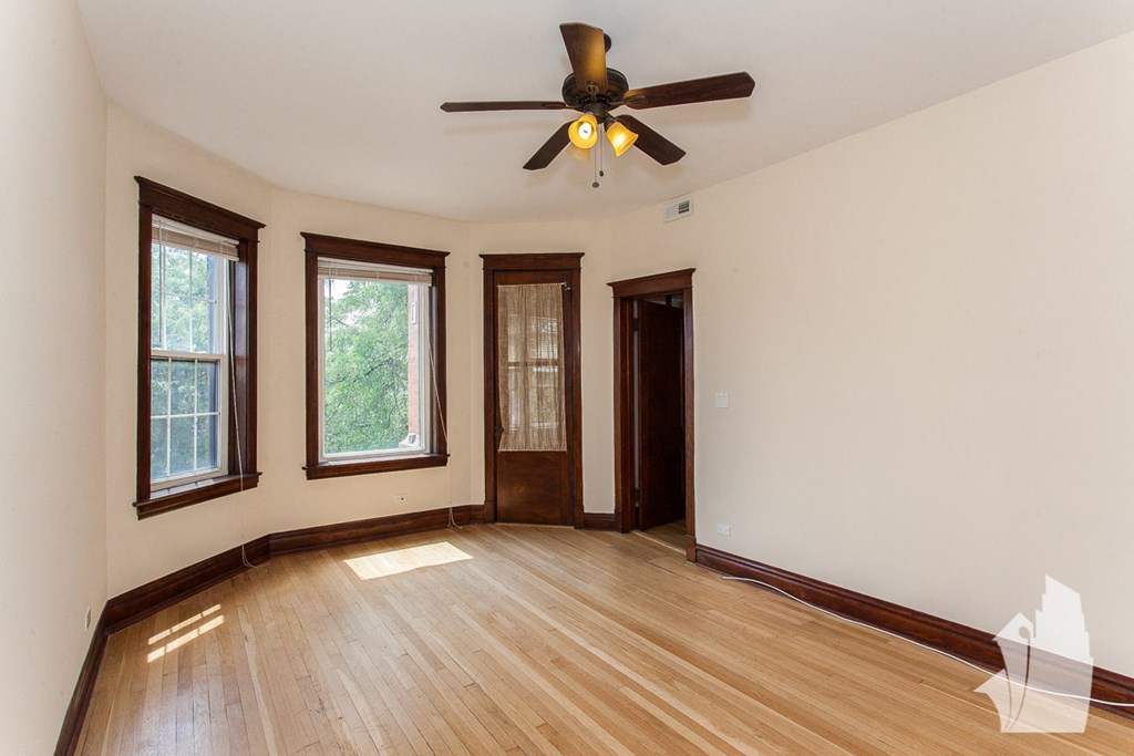 an empty living room with wood floors and a ceiling fan