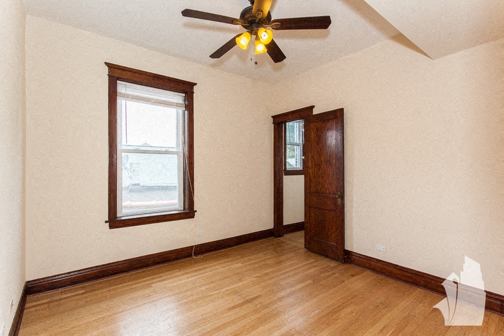 an empty living room with a ceiling fan and a window