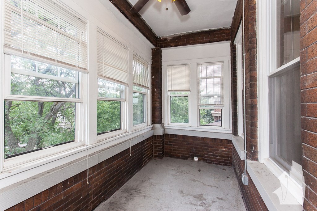 an empty room with three windows and a ceiling fan