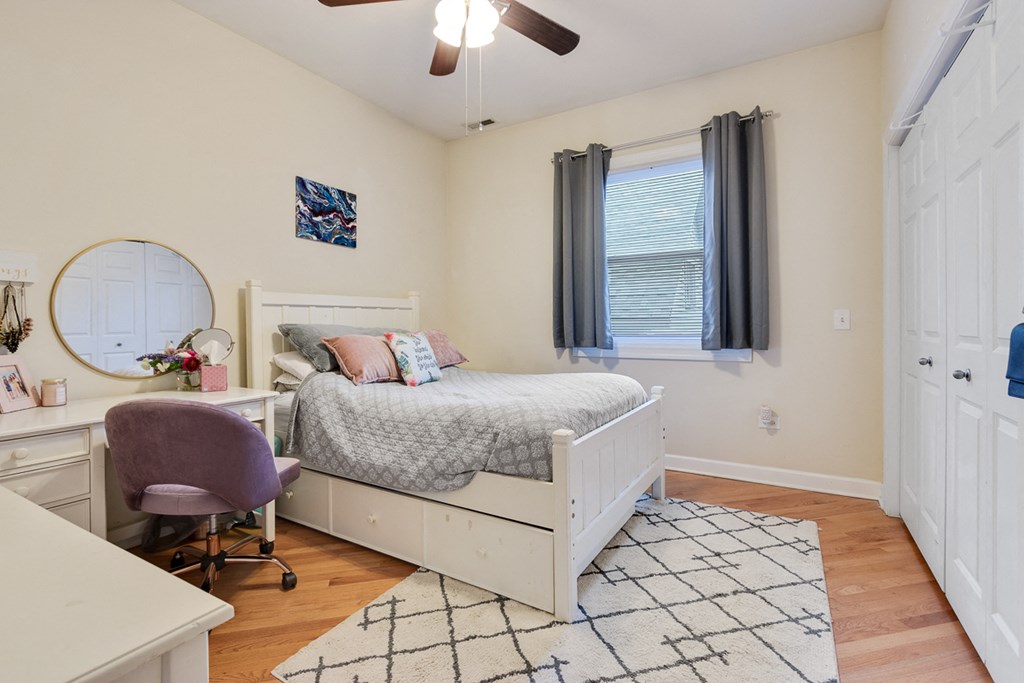 a bedroom with a bed and a desk and a window