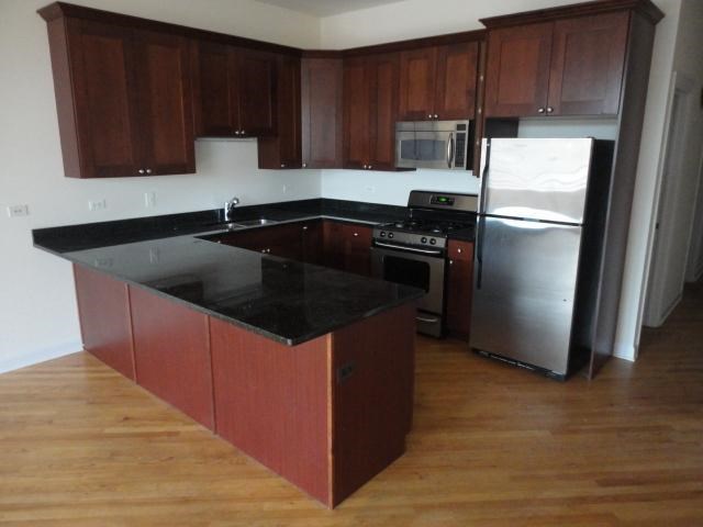 a kitchen with a black counter top and a refrigerator