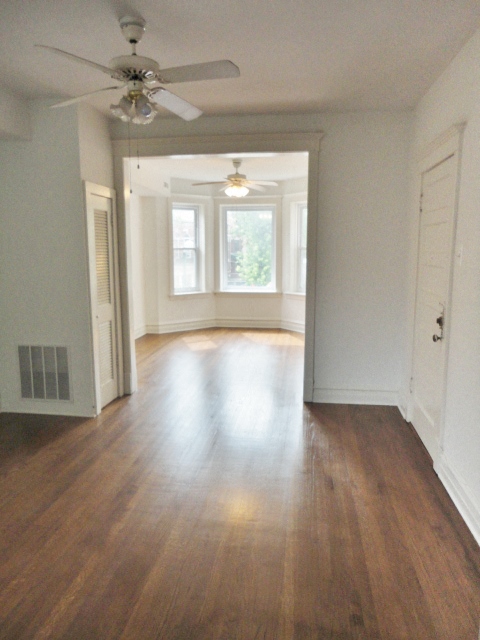 an empty living room with wood floors and a ceiling fan
