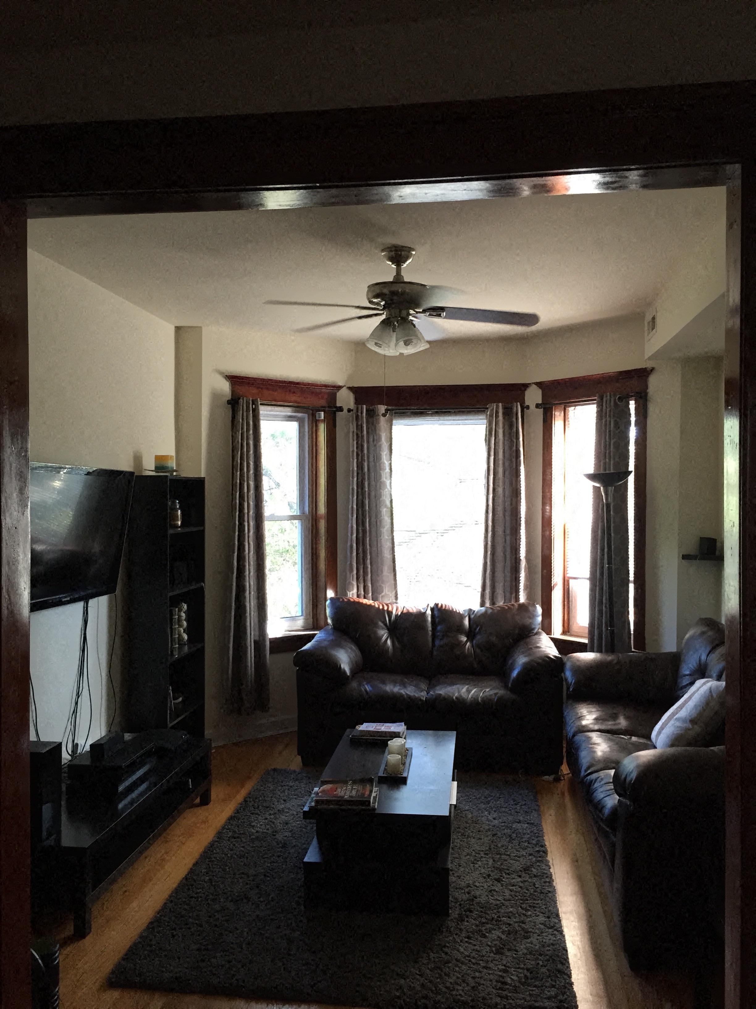 a living room with leather furniture and a ceiling fan