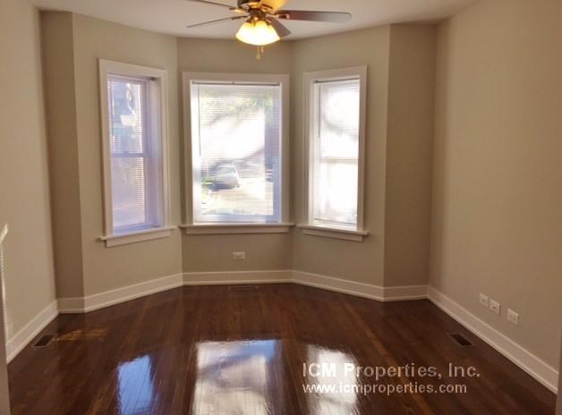 a empty living room with a ceiling fan and three windows