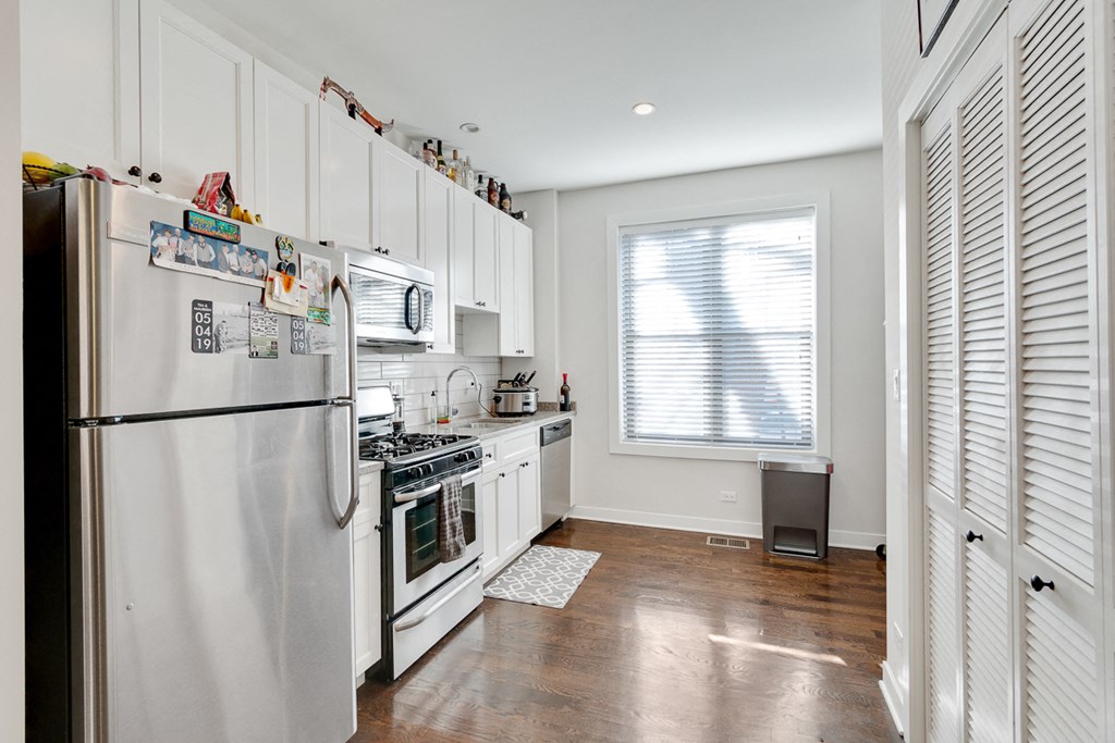 a kitchen with white cabinets and stainless steel appliances and a window