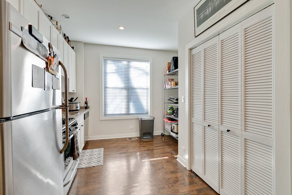 a kitchen with white cabinets and a refrigerator and a window
