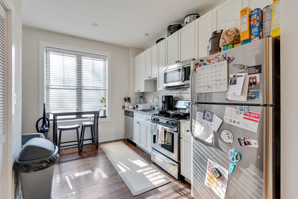 a kitchen with white cabinets and appliances and a refrigerator
