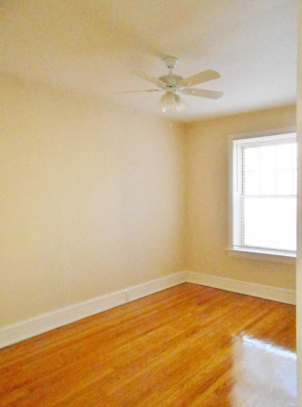 an empty room with a ceiling fan and a window