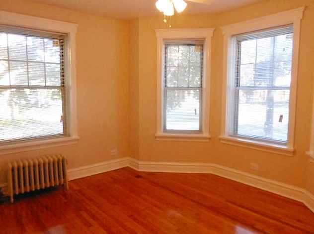 a living room with a wooden floor and three windows