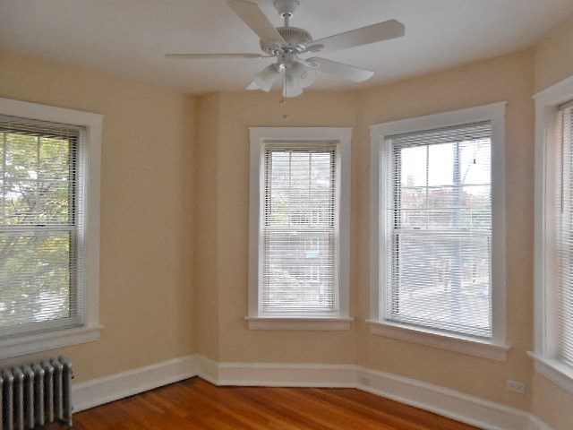 a living room with three windows and a ceiling fan