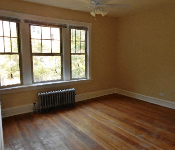 an empty living room with a wood floor and three windows