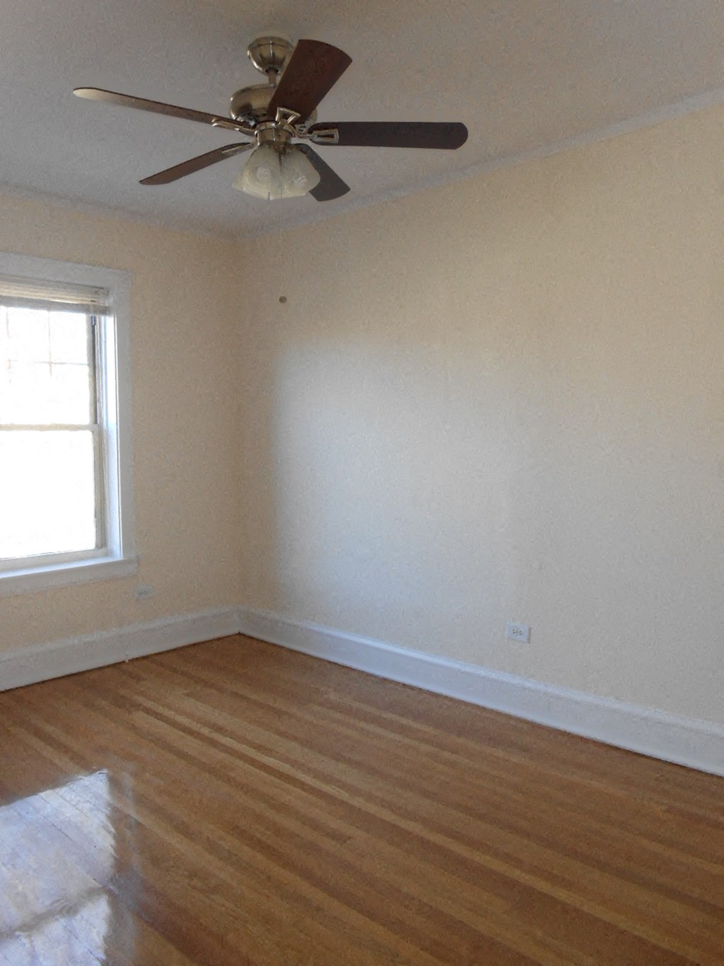 an empty room with a ceiling fan and a window
