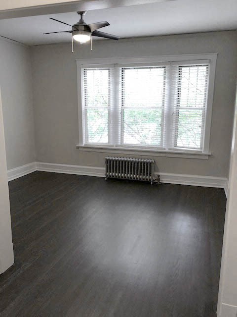 an empty living room with a ceiling fan and a window