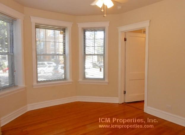 an empty living room with three windows and a door