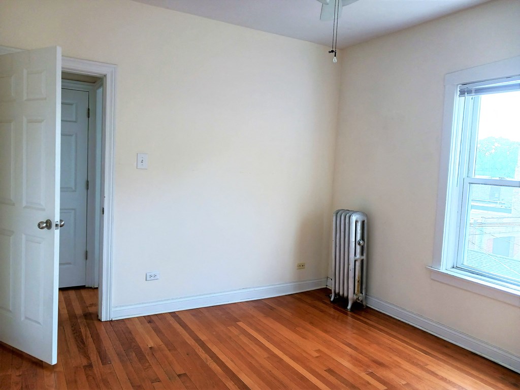 an empty room with wood floors and a radiator and a door