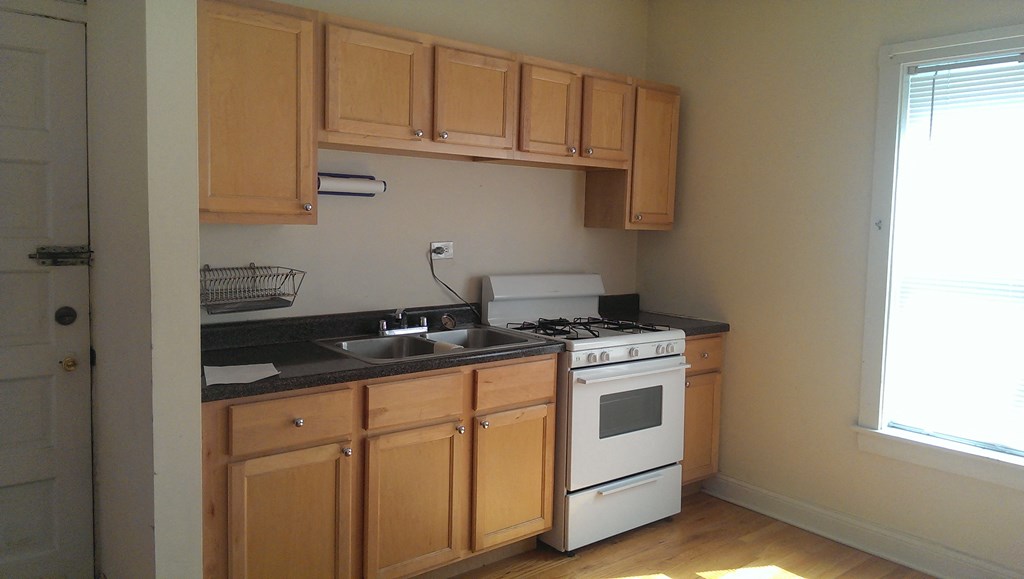 a kitchen with wooden cabinets and a white stove and sink