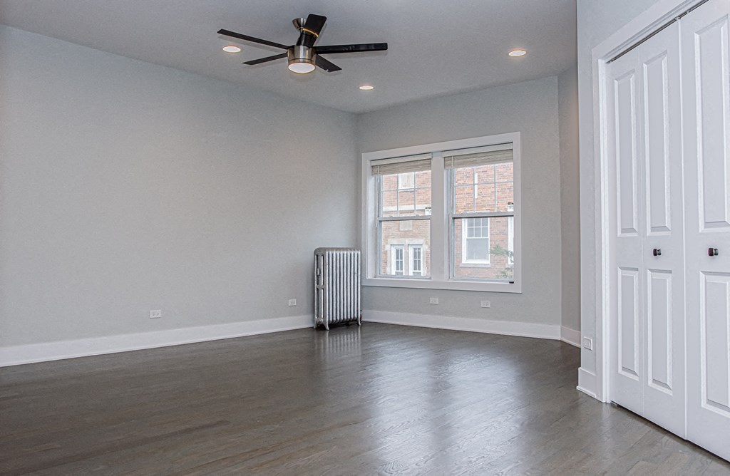 an empty living room with a ceiling fan and a window