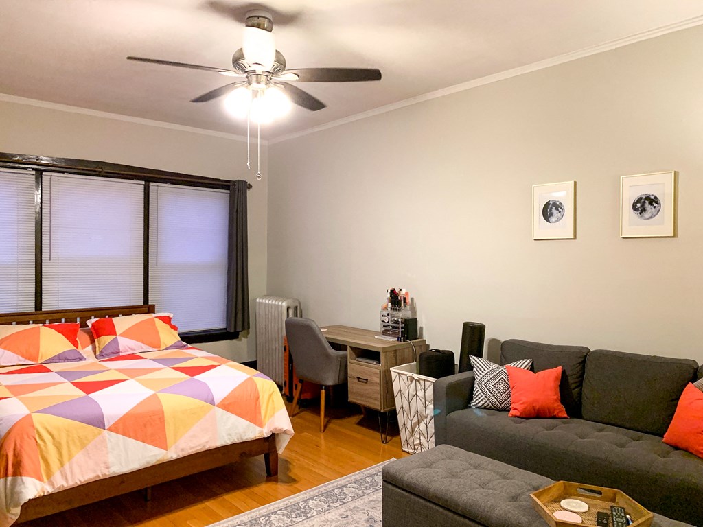 a bedroom with a couch and a bed and a ceiling fan