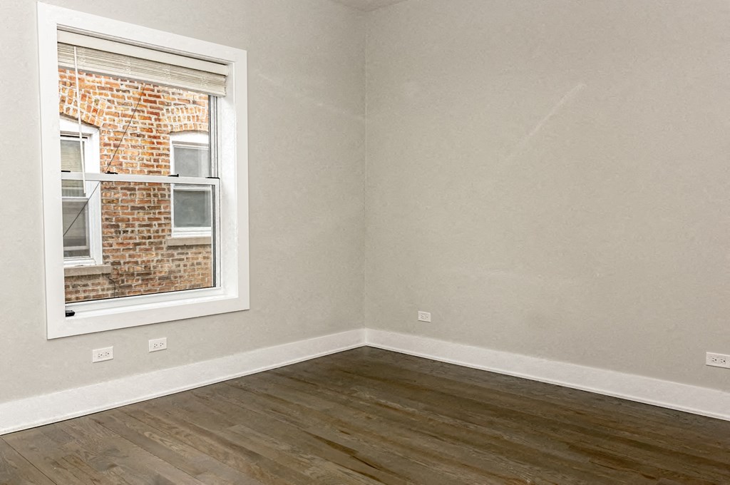 an empty room with a window and wooden floors