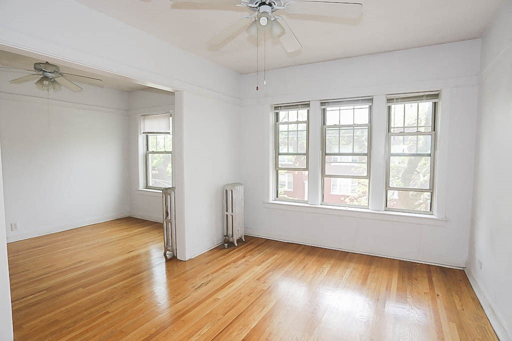 an empty room with wood floors and a ceiling fan
