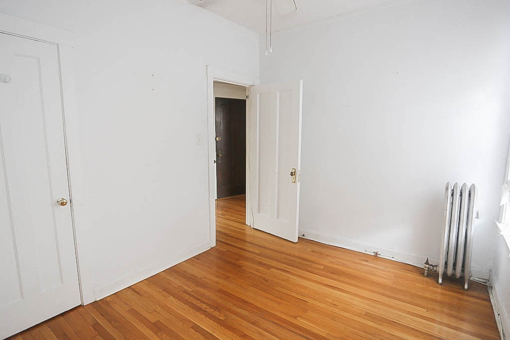 a room with a wood floor and white walls and a radiator