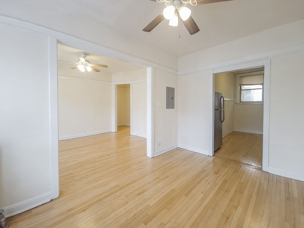 an empty living room with wood flooring and a ceiling fan