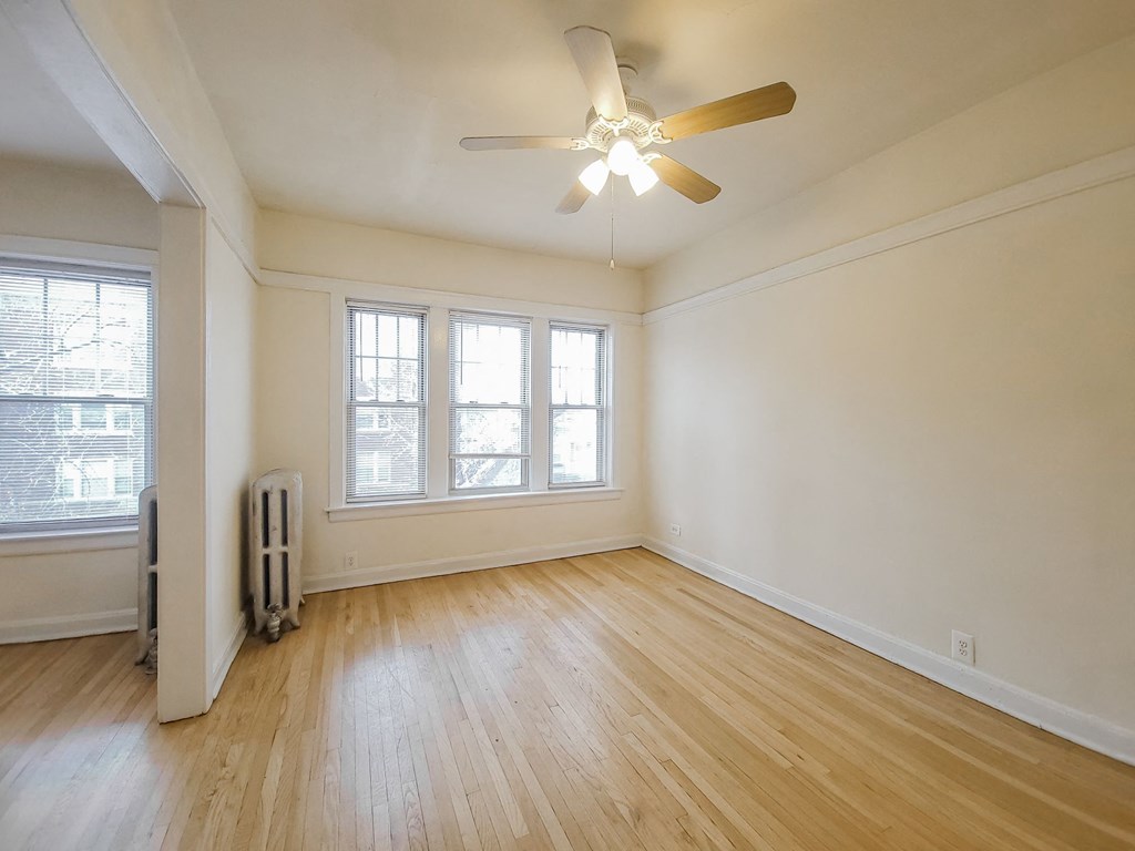 an empty living room with wood floors and a ceiling fan