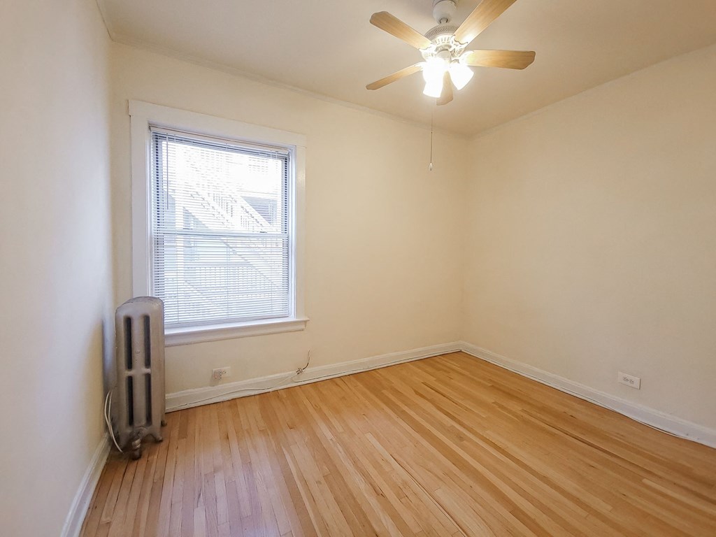 an empty room with wooden floors and a ceiling fan