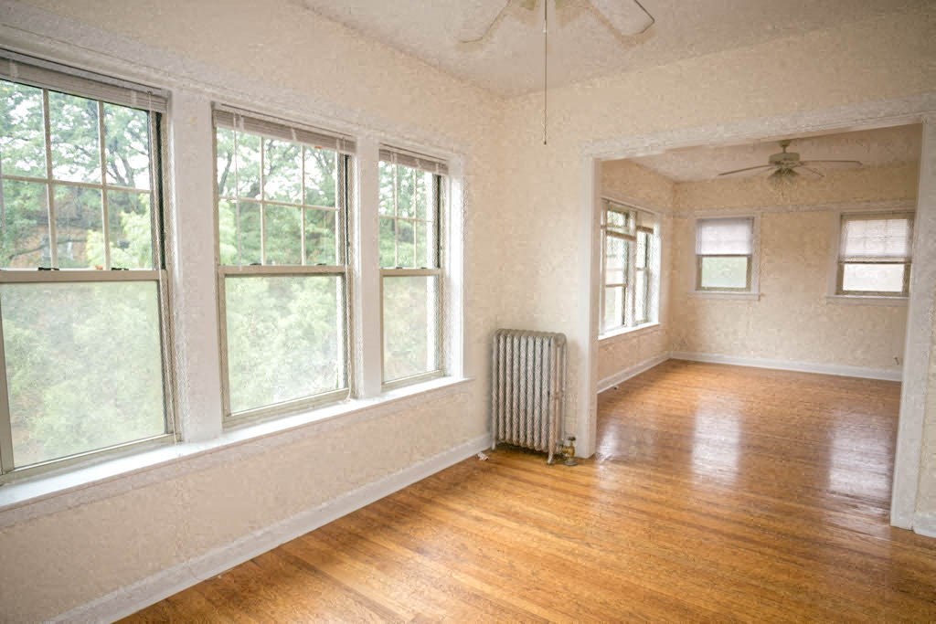 an empty living room with a radiator and wood floors