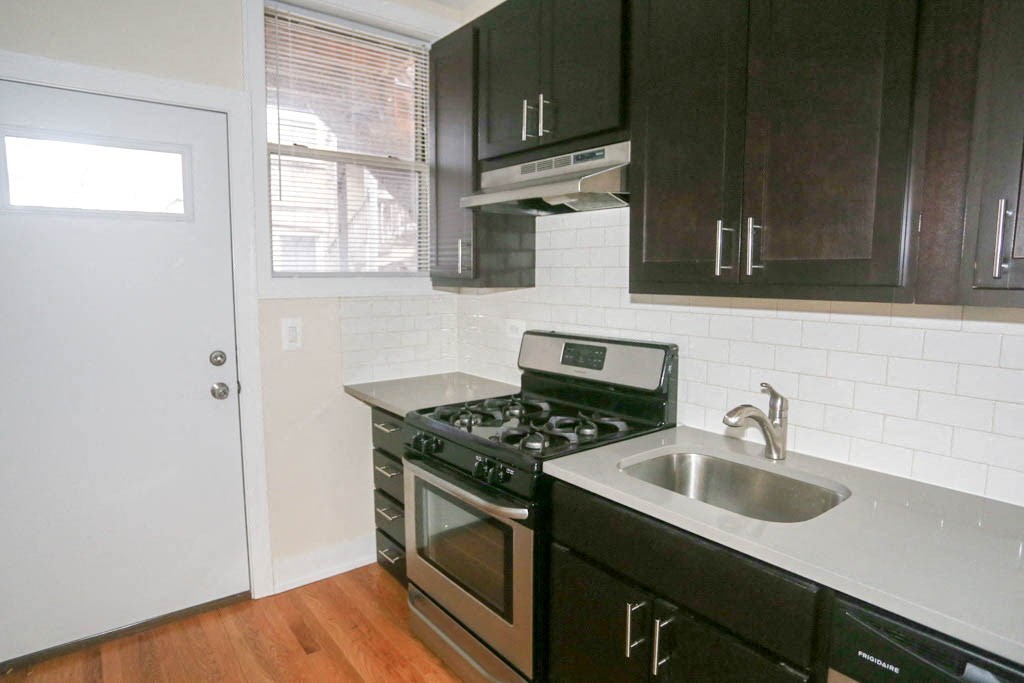 a kitchen with black cabinets and a sink and a stove