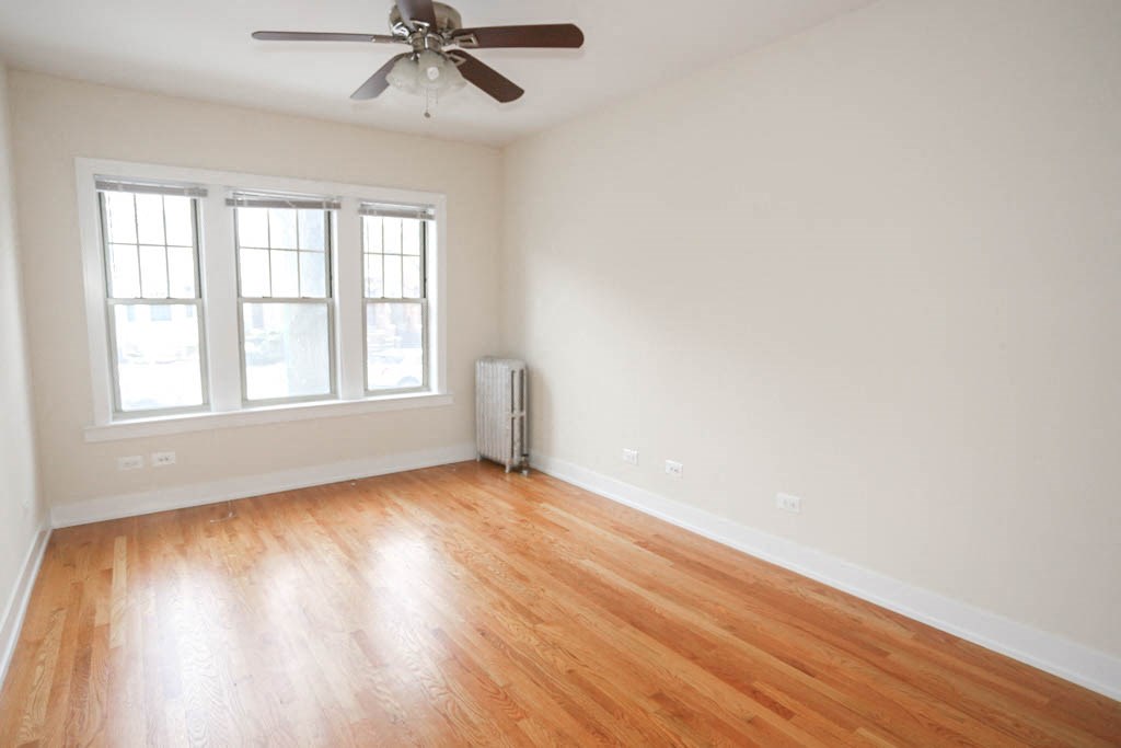 an empty living room with wood floors and a ceiling fan