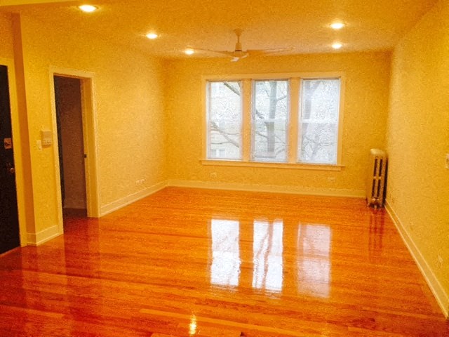 an empty living room with a wooden floor and a window
