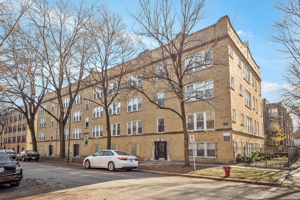 a brick apartment building with cars parked in front of it