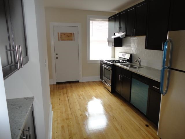 a kitchen with wooden floors and black cabinets