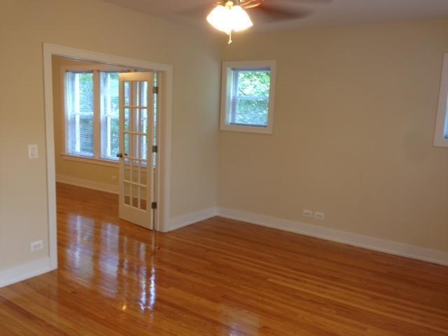 an empty living room with a wood floor and a ceiling fan
