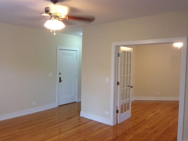 an empty living room with a ceiling fan and a door