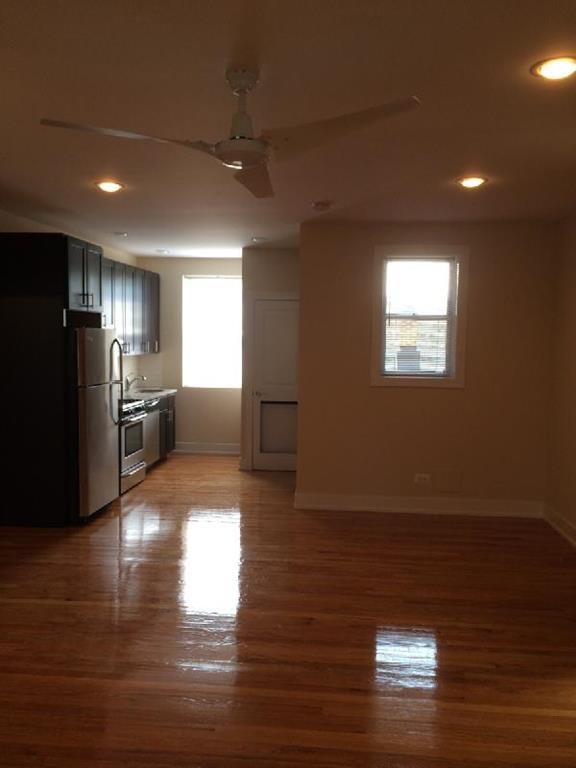 an empty kitchen with a wood floor and a refrigerator