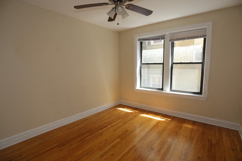 an empty room with a ceiling fan and a window