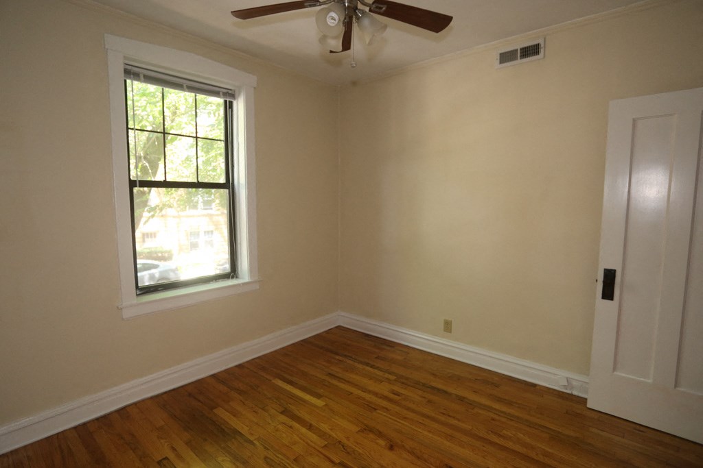 an empty bedroom with a ceiling fan and a window