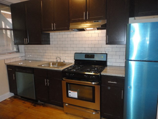 a kitchen with black cabinets and stainless steel appliances