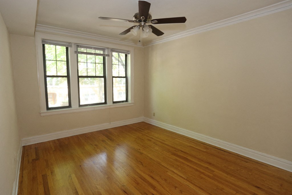 an empty living room with wood floors and a ceiling fan