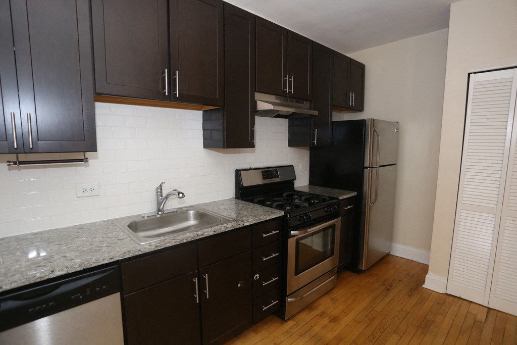 an empty kitchen with black cabinets and stainless steel appliances