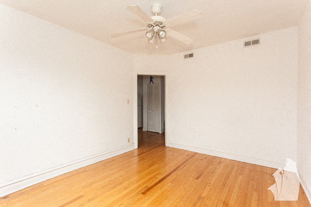 an empty room with a ceiling fan and wood floors